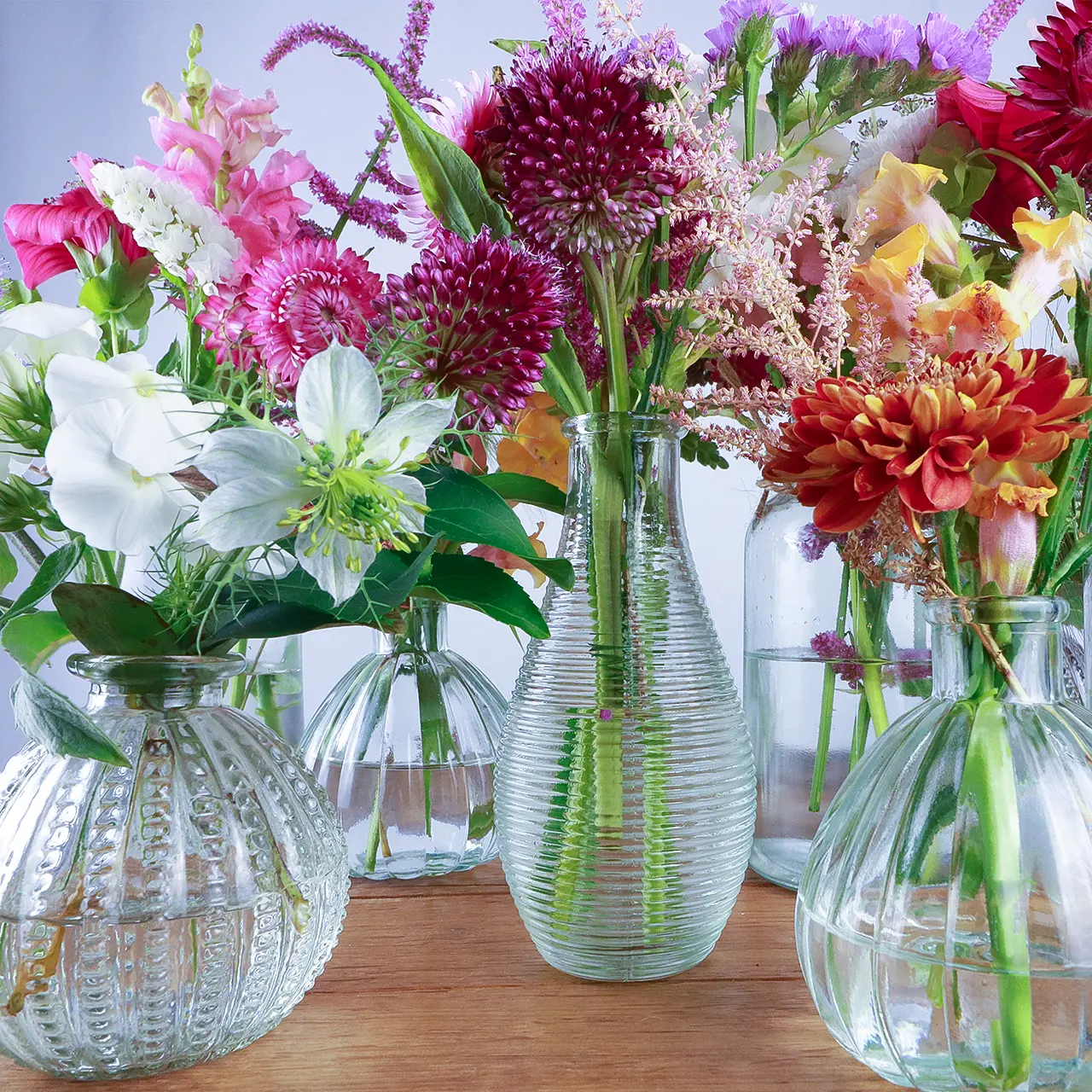Collection of various glass bud vases filled with vibrant sustainably-grown Devon flowers from Marguerite Rose florist and flower farmer