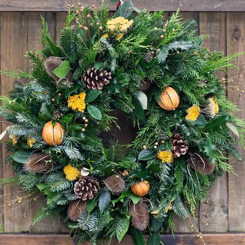 Full Christmas wreath with natural evergreen foliage, pinecones, and dried oranges from Marguerite Rose Devon.