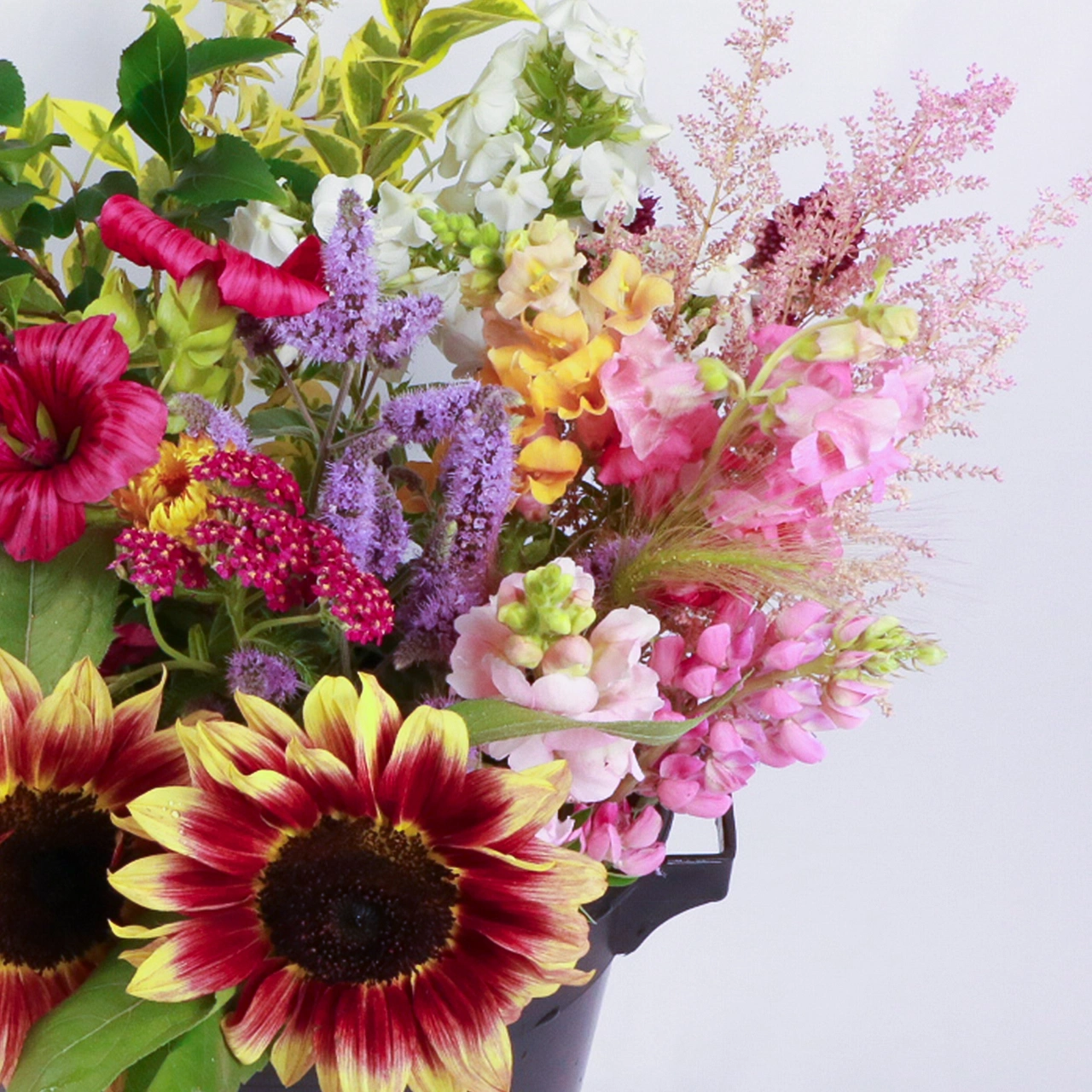 DIY Flower Bucket 3 Right side close-up of Marguerite Rose DIY flower bucket, featuring a vibrant array of freshly picked Devon-grown flowers: sunflowers, delicate pink sweet peas, white stocks, purple statice, red celosia, and feathery astilbe.
