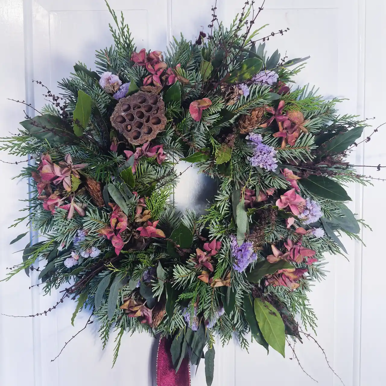 The Enchanted Garden large moss Christmas wreath with pine, lotus pods, purple statice, bay leaves and burgundy foliage handmade in Devon