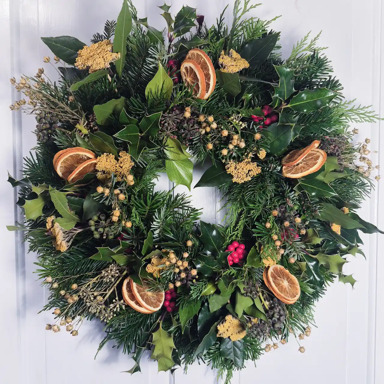 The Exe Valley large moss Christmas wreath with pine, holly, ivy, bay leaves, dried orange slices, golden achillea and red holly berries handmade in Devon