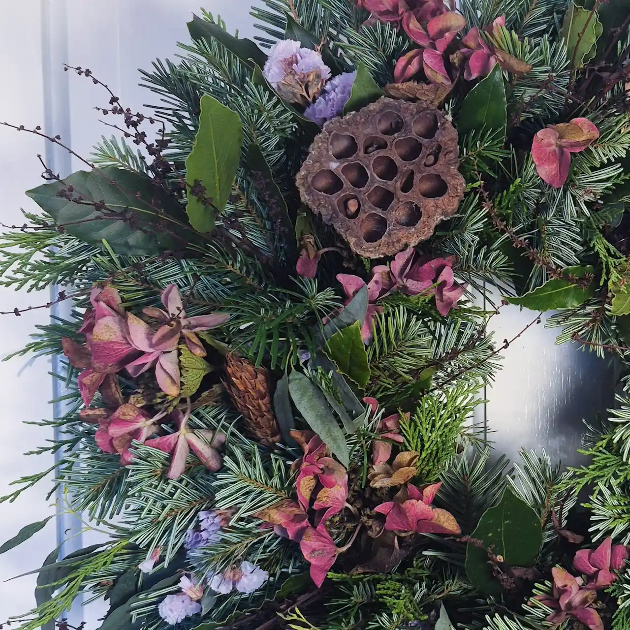 Close-up of handmade Devon Christmas wreath showing lotus pods, purple dried statice, burgundy hydrangea and pine