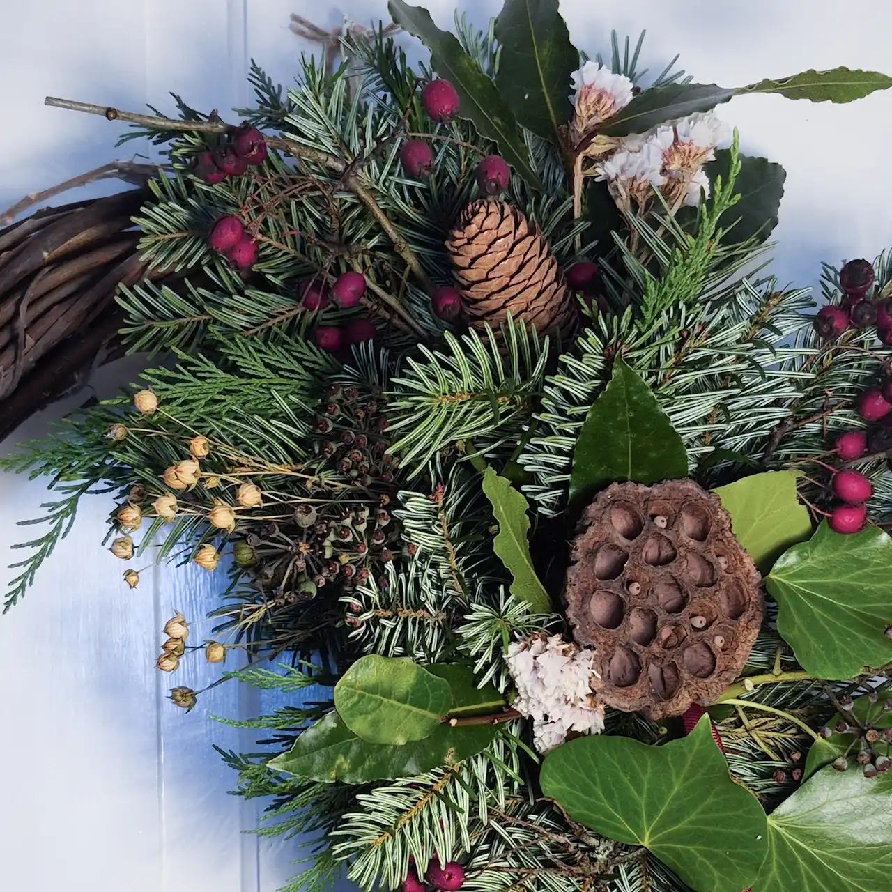 Close-up of Devon willow Christmas wreath featuring burgundy hawthorn berries, fir cones, lotus pods, ivy and pine
