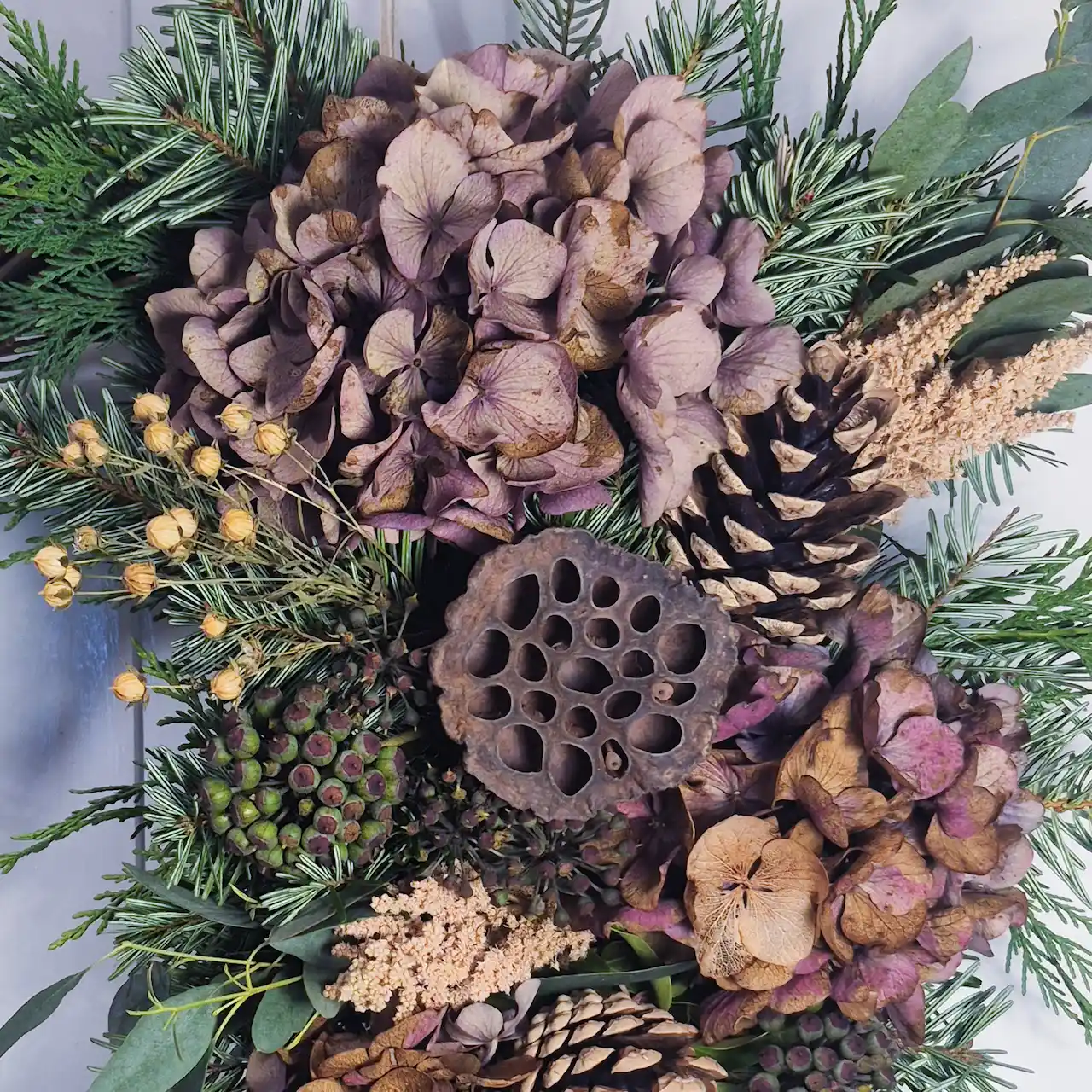 Close-up of Devon willow Christmas wreath featuring dried purple hydrangea, lotus pods, fir cones and pine
