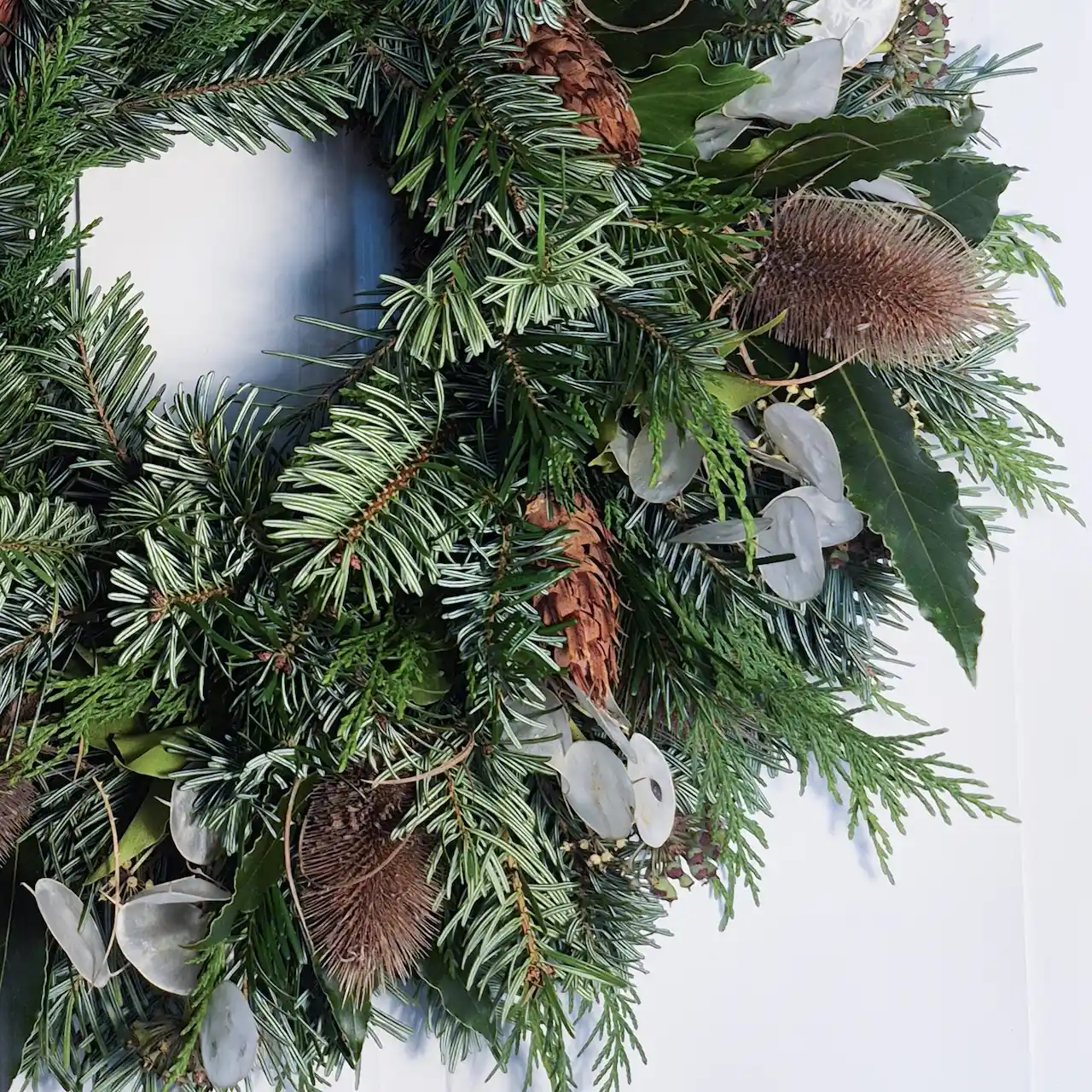 Close-up of Devon Christmas wreath featuring honesty seed pods, teasels, banksia, bay leaves, ivy and pine