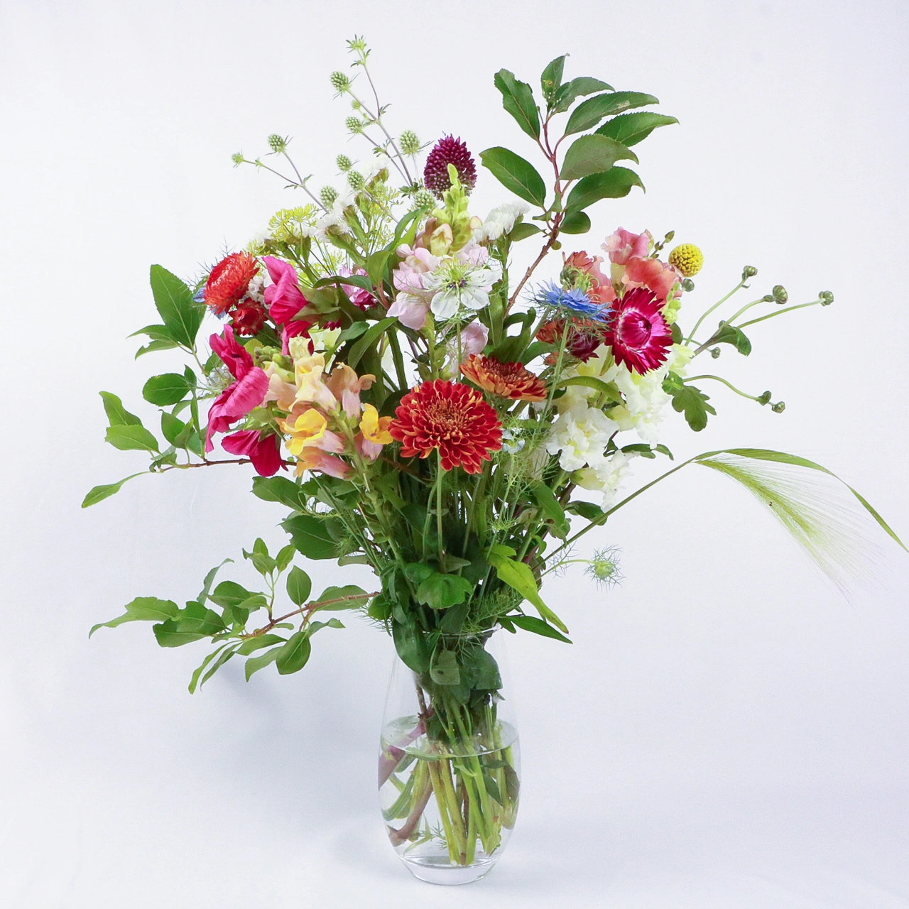 Marguerite Rose medium seasonal bouquet with red dahlias, pink cosmos, white nigella, and mixed foliage in glass vase