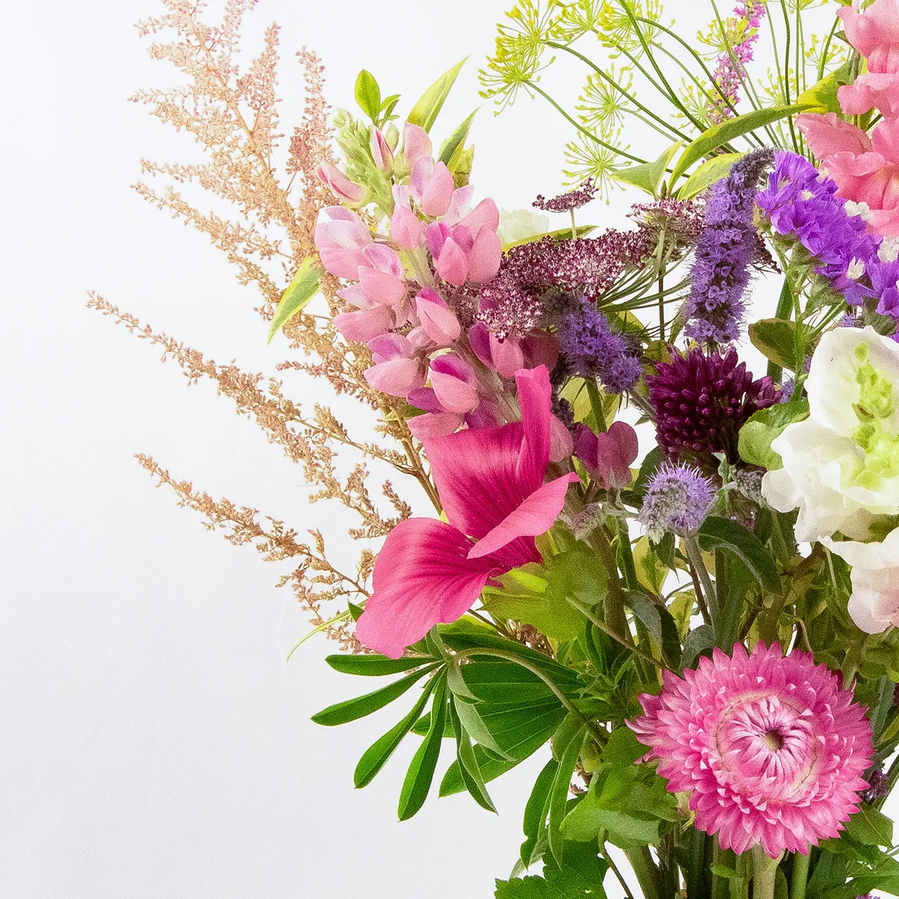 Sweetheart Bunch 2 Close-up view of the left side of a standard size seasonal flower bouquet by Marguerite Rose, a Devon florist. Features pink lupins, bronze astilbe, and vibrant mixed seasonal flowers.