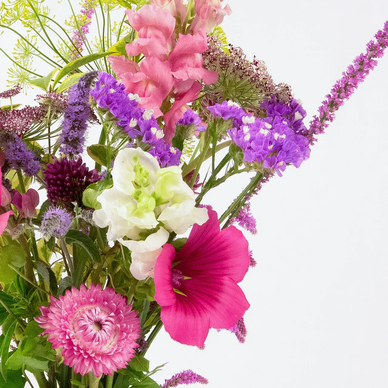 Close-up view of the right side of a standard size seasonal flower bouquet by Marguerite Rose, a Devon florist. Features pink snapdragons, purple statice, and other vibrant seasonal blooms.